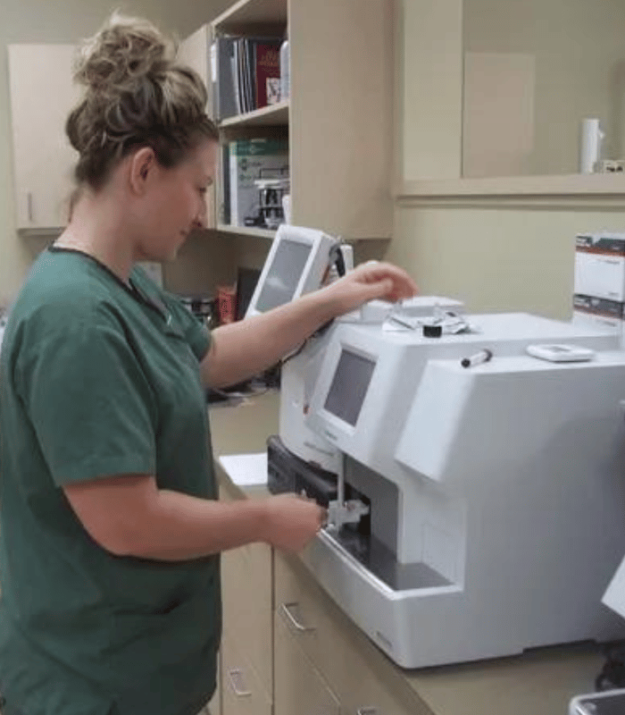 A vet in a lab coat engages with a machine